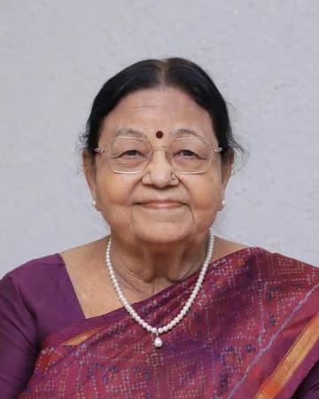 Portrait of Mrs. Ranjan Broker, wearing glasses, a pearl necklace and a purple patola saree